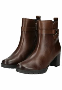 Bottines en cuir marron avec une texture lisse, fermeture éclair sur le côté et une sangle décorative avec une boucle en métal. Talon bloc pour plus de stabilité.