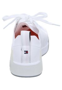 Zapatilla blanca con parte superior sintética lisa, punta redonda, diseño con cordones y un interior rojo. Cuenta con una lengüeta de talón con marca y suela de goma.
