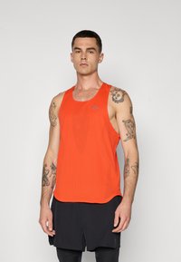 Orange, sleeveless athletic tank top made of mesh fabric, featuring a round neckline and a subtle logo. Worn with dark shorts.
