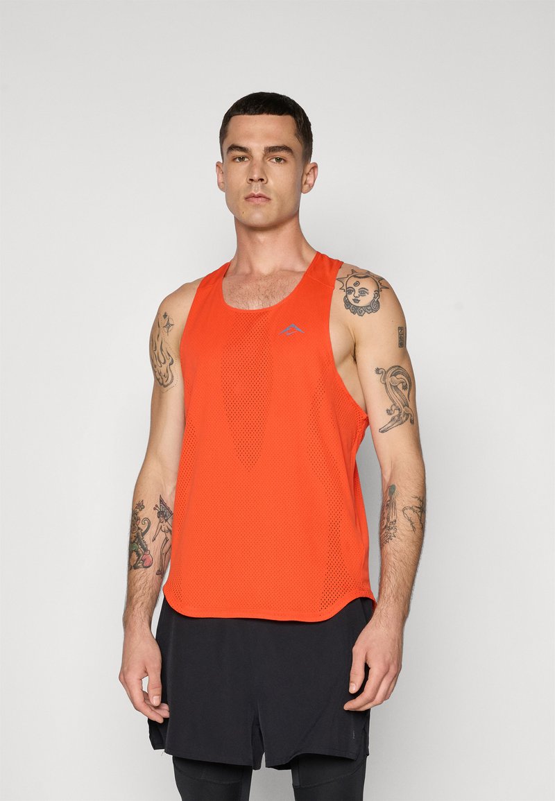 Orange, sleeveless athletic tank top made of mesh fabric, featuring a round neckline and a subtle logo. Worn with dark shorts.