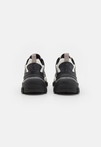 Baskets de sport noires et grises avec un dessus texturé, une semelle rembourrée et un tirant contrasté à l'arrière. Logo "MICHAEL KORS" à l'arrière.