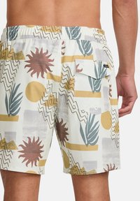 Costumi da bagno da uomo in tessuto leggero, con un motivo geometrico e botanico colorato in beige, verde, marrone e giallo.