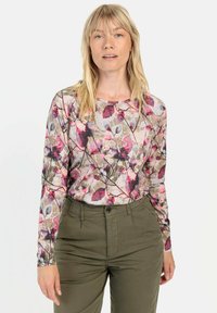Langärmliges Oberteil mit floralem Muster in Rosa-, Lila- und Grüntönen, aus leichtem Stoff, kombiniert mit olivfarbenen Cargo-Hosen.