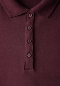 Mörkröd polo skjorta med en texturerad tyg. Har en krage och fem matchande knappar fram, vilket visar en klassisk design.