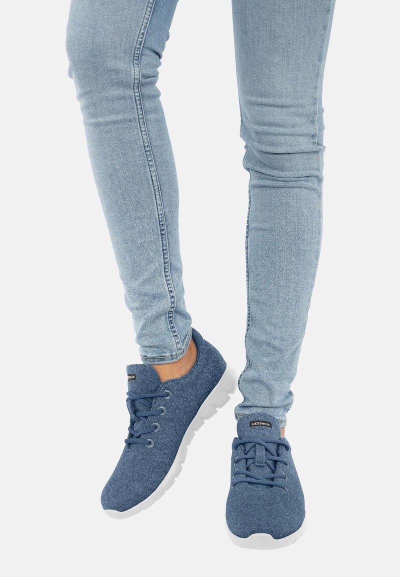 Blaue Stoff-Sneaker mit weicher Textur, weißer Gummisohle und Schnürdesign. Getragen mit hellblauen Skinny-Jeans.