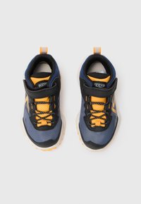 Blue and black athletic shoes with orange accents, textured upper, adjustable Velcro strap, and contrasting laces.