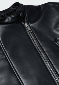 Veste en cuir noire avec fermeture éclair argentée à l'avant et col à bouton-pression, montrant une texture lisse et des détails de design élégants.