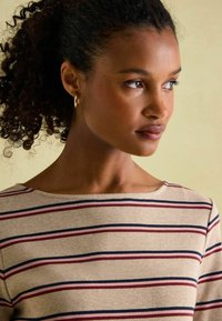 Beiger Oberteil mit horizontalen Streifen in Burgunderrot und Marineblau, mit weitem Ausschnitt und kurzen Ärmeln, strukturierter Strickstoff und subtilen Nahtdetails.