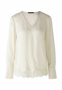 Cremefarbene Bluse mit langen Ärmeln, V-Ausschnitt und einer Spitzenborte am Saum. Glattes Gewebe mit subtiler Natürlichkeit, mit einer mittigen Nahtdetails.