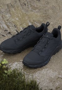 Czarne buty sportowe z teksturowanym syntetycznym cholewką, systemem sznurowadeł i wyściełanymi podeszwami, charakteryzujące się gładkim wykończeniem i trwałą konstrukcją.