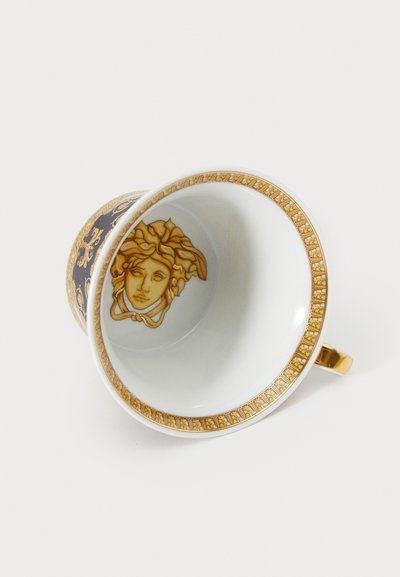 Posliinikuppi mustalla ulkopuolella, kultakoristelulla ja Medusa-aiheisella kuvalla sisällä. Pyöreä muoto ja kultainen kahva.