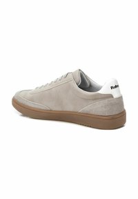 Zapatillas de gamuza gris claro con suela de goma, diseño con cordones y una pestaña en el talón blanca. Presentan acentos texturizados y un perfil minimalista.