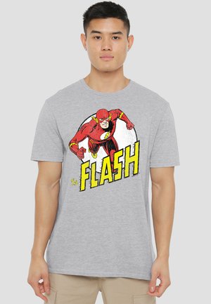 Young man wearing light gray t-shirt featuring a red Flash superhero graphic in a running pose with bold yellow text "The Flash."