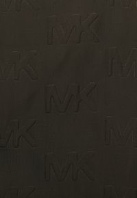 Sort tekstureret stof med et gentaget præget "MK" logo mønster, der skaber en subtil kontrast på overfladen. Holdbar og glat finish.