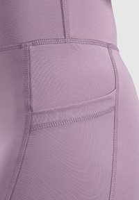 Leggings en lavanda claro, fabricados con una tela suave y elástica. Presentan costuras planas y un bolsillo lateral para el almacenamiento.