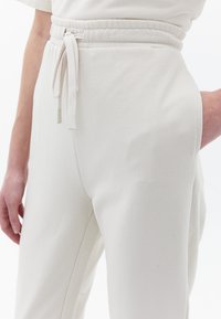 Lichtgekleurde joggerbroek met een trekkoord in de taille, gemaakt van zachte stof. Voorzien van zijzakken en een taps toelopend beenontwerp.