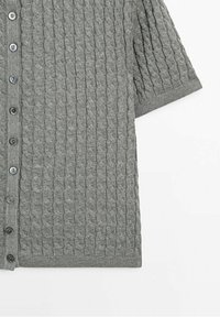 Cardigan gris à manches courtes en tricot avec un motif torsadé et une rangée frontale de boutons noirs sur un fond blanc.