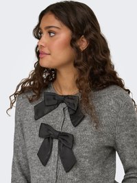 Gray knit cardigan featuring two large black satin bows at the neckline, textured fabric, and button closure at the front.