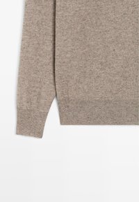 Beżowy sweter z kaszmiru z okrągłym dekoltem, prążkowanymi mankietami i dołem oraz miękką teksturą w delikatny melanż.