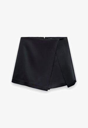 Mini-jupe asymétrique noire avec effet portefeuille et fermeture éclair cachée à l'arrière, tissu lisse avec une légère brillance.