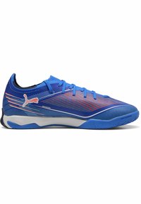 Blaue, niedrig geschnittene Puma Sportschuhe mit orangenen Akzenten, weißer Zwischensohle, strukturierter Sohle und Schnürverschluss, entworfen für den Innenbereich.