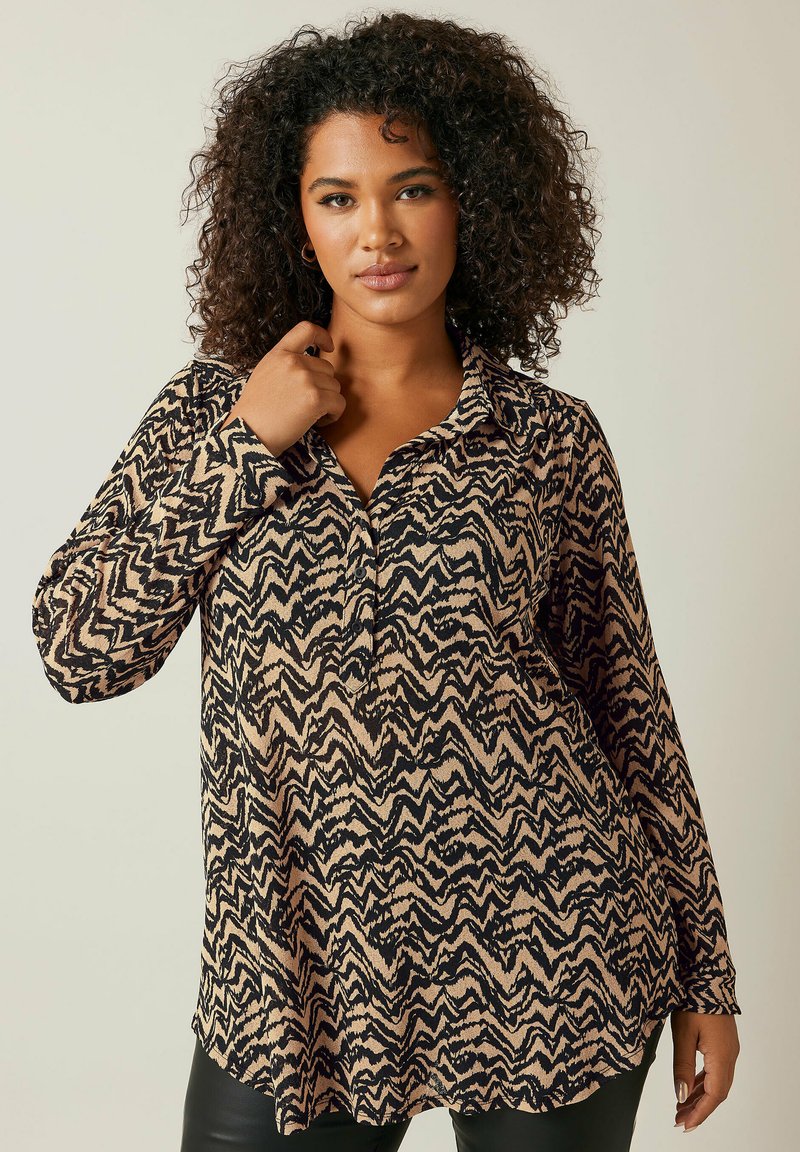 Camicia a maniche lunghe beige con un motivo a zigzag nero. Presenta un colletto e una vestibilità morbida, realizzata in un materiale morbido e testurizzato.