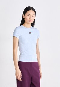 T-shirt in cotone azzurro chiaro a maniche corte con design aderente, caratterizzato da un piccolo logo multicolore sul petto. Silhouette snella, texture morbida.