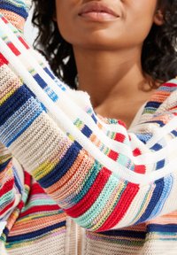 Cárdigan de punto con rayas multicolores en rojo, azul, amarillo y blanco. Tejido suave y texturizado con capucha y diseño de frente abierto.