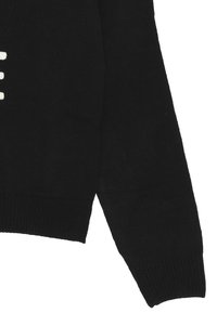 Maglione nero lavorato a maglia con maniche lunghe e orlo a coste. Lettering di colore chiaro ben visibile sulla parte anteriore.