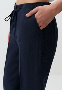 Navy linnen broek met een ontspannen pasvorm, voorzien van een koord in de taille en zijzakken, met een zachte textuur en strakke lijnen.