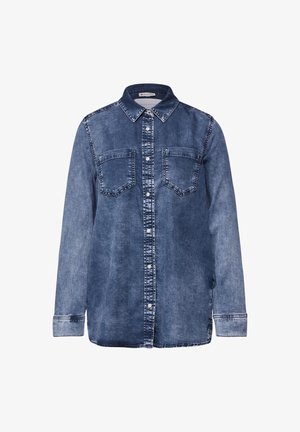 Koszula dżinsowa z klasycznym kołnierzykiem, długimi rękawami i dwiema kieszonkami na piersi. Materiał w średnim odcieniu niebieskiego z jaśniejszymi przejaśnieniami i białymi szwami.