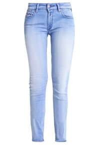 Jeans skinny de denim azul claro con acabados desgastados, cinco bolsillos, pasadores para cinturón y cierre de botón. Textura suave y diseño de ajuste ceñido.