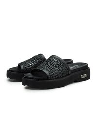 Sandali slide neri tessuti con una tomaia testurizzata, suola piatta e una fascia larga. Presentano una base piattaforma e un sottile logo sul lato.