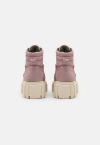 Botas de ante rosas hasta el tobillo con un collar acolchado, suela gruesa en beige claro y tira en la parte posterior para facilitar el calzado. Material texturizado con un acabado suave.