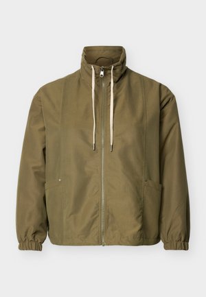 Veste zippée vert olive avec col montant, cordons blancs, poignets élastiques et poches latérales sur un fond clair uni.