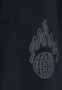 Μαύρος ύφασμα με λεία υφή, που παρουσιάζει μια μεγάλη γκρι απεικόνιση φλόγων πάνω από έναν σχεδιασμό σφαίρας στην δεξιά πλευρά.