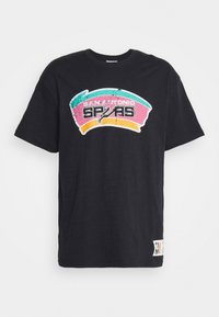 T-shirt nera con un logo vintage dei San Antonio Spurs in teal, rosa e giallo sul petto e una piccola toppa vicino all'orlo.