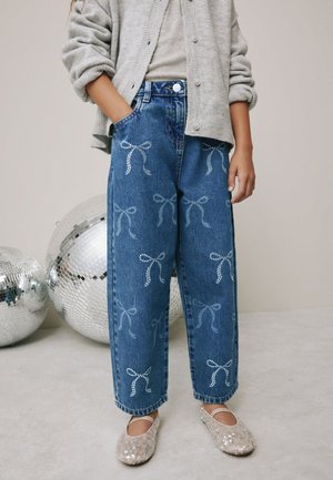 Denim jeans met een losse pasvorm, voorzien van lichtblauwe strikpatronen en zilveren pailletten. Gecombineerd met een grijze cardigan en glinsterende beige platte schoenen.
