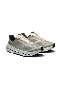 Helle graue Sportschuhe mit einem Mesh-Obermaterial, strukturierten Akzenten, einer weißen Dämpfungssohle und einer schwarzen Gummi-Außensohle. Mit auffälliger Markenkennzeichnung.