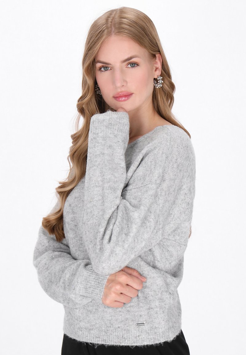 Grauer gestrickter Pullover mit weitem Halsausschnitt, gerippten Bündchen und weicher Textur. Er besitzt einen dezenten Glanz und ein kleines Logodetail am Saum.