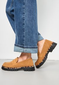 Suède loafers in lichtbruin met een zwarte chunky zool, voorzien van een luipaardprint detail en een soepel instapontwerp. Verhoogde casual schoeisel.