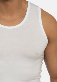 Biała tank top wykonana z miękkiej, lekkiej tkaniny, charakteryzująca się okrągłym dekoltem i dopasowanym krojem. Brak widocznych wzorów lub ozdób.