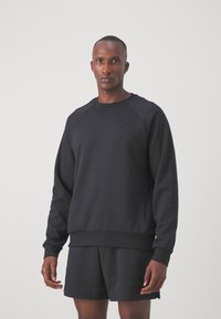 Sweat-shirt noir avec un col rond et des poignets côtelés, fabriqué en tissu doux avec un logo Nike discret sur le devant.