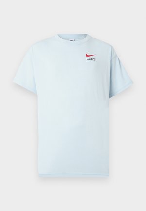 Tricou din bumbac de culoare albastru deschis, cu mâneci scurte, guler rotund și logo-ul roșu Nike swoosh. Textul spune "DEPARTAMENT SPORTIV. FĂ-O!"