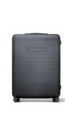 Dark gray hard-shell suitcase with horizontal grooves, four wheels, and a small rectangular handle on top against a white background.