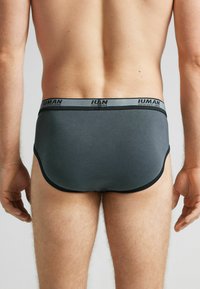 Donkergrijze herenenkels met een zwarte tailleband. Gemaakt van gladde stof, met een strakke pasvorm en een minimalistisch ontwerp. Geen zichtbare patronen of accenten.