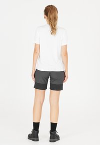 Vit kortärmad skjorta, grå shorts med mörkare fåll, kombinerat med svarta ankelstövlar och strumpor, sedd från baksidan mot en vit bakgrund.