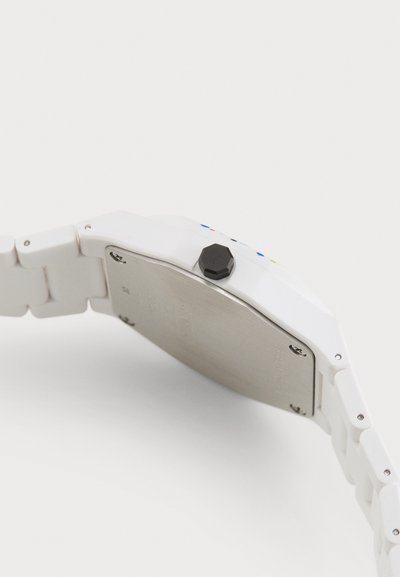 Montre en plastique blanche avec une finition lisse, arborant une couronne hexagonale noire et un dos en acier inoxydable argenté. Accents multicolores sur le cadran.