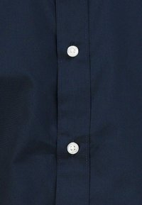 Camicia blu navy con bottoni bianchi in plastica, texture liscia e design elegante con colletto classico.