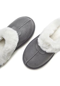Gray slippers made of soft suede with a faux fur lining. Features a round toe and stitched detailing along the seams.